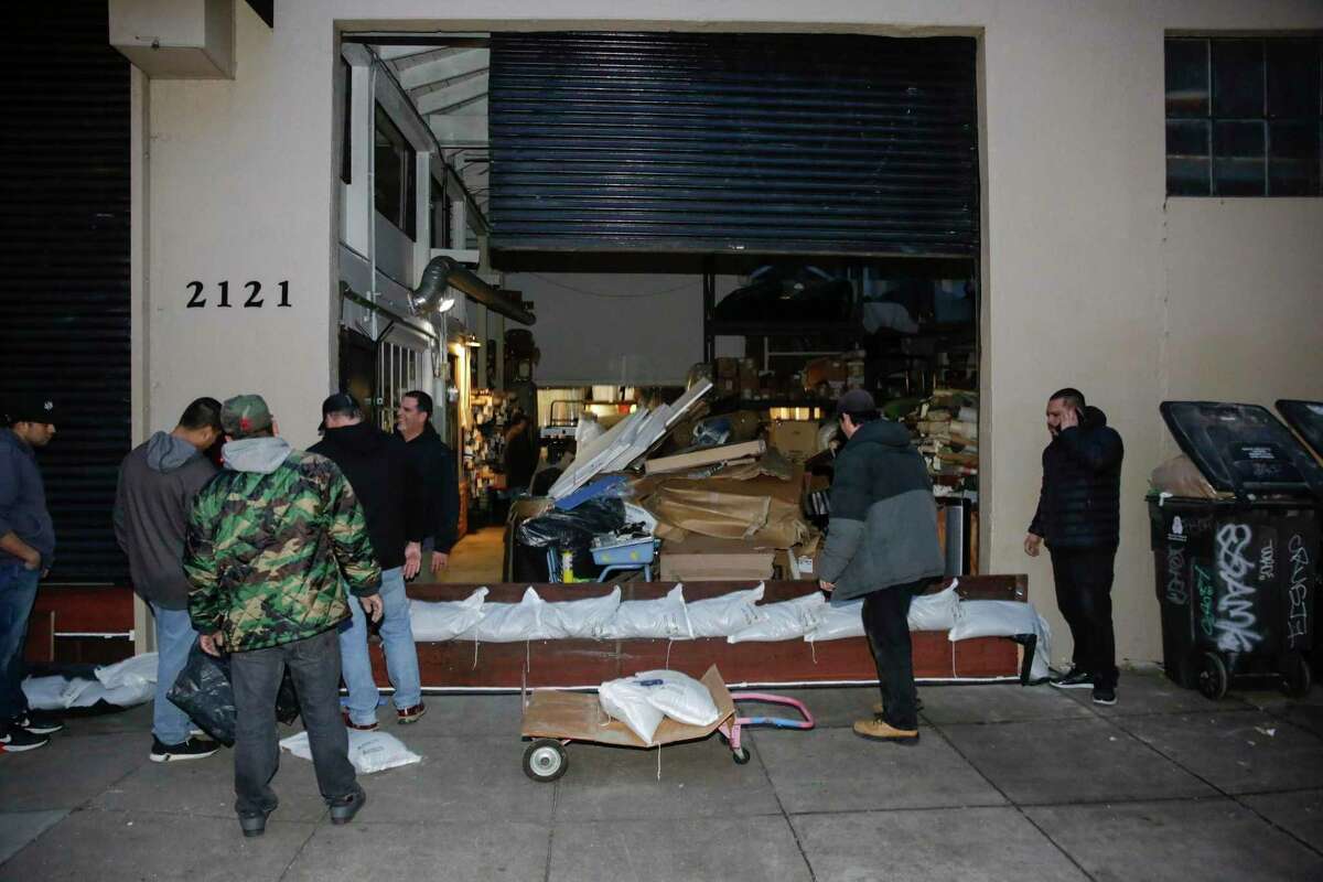 Employees form a makeshift barrier outside Hilde Brand furniture in the Mission Disrict on Tuesday. A local ordinance passed three years ago dramatically limits the city’s settlements with business and homeowners over flood damage.