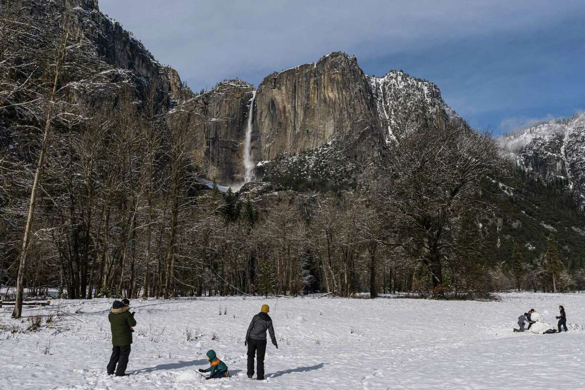 Park visitors make a snowman in a meadow near Yosemite Falls in Yosemite National Park on Friday. Waterfalls are coursing after recent storms dumped snow and rain in the Sierra Nevada mountains.
