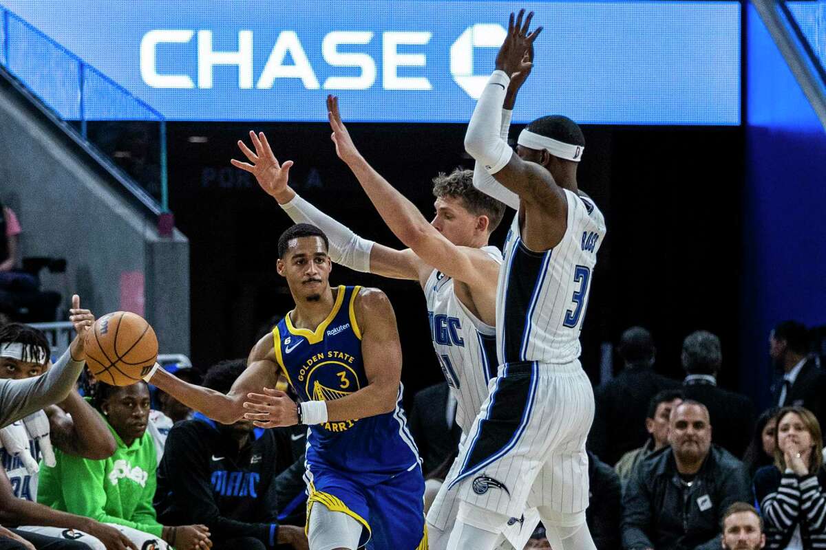 Golden State Warriors guard Jordan Poole (3) makes a pass as he is defended by Orlando Magic center Moritz Wagner (21) and guard Terrence Ross (31) during the second half of their NBA basketball game in San Francisco, Calif. Saturday, Jan. 7, 2023. The Magic defeated the Warriors 115-101.