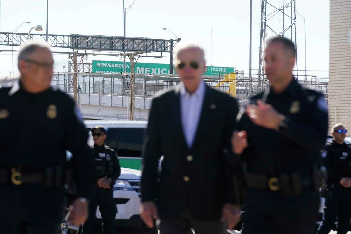 A large "Welcome to Mexico" sign hung over the Bridge of the Americas is visible as President Joe Biden, center, talks with a U.S. Customs and Border Protection officer as he tours the El Paso port of entry, a busy port of entry along the U.S.-Mexico border, in El Paso Texas, Sunday, Jan. 8, 2023.