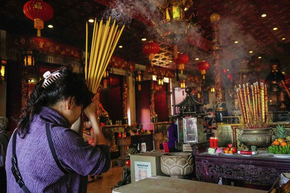 Susan Huynh brings a handful of lit incense as an offering of gratitude and to wish for peace and health for the coming year at the Ong Bon Festival and Eye Dot ceremony on Sunday, Jan. 8, 2023 at Texas Teo Chew Temple in Houston.