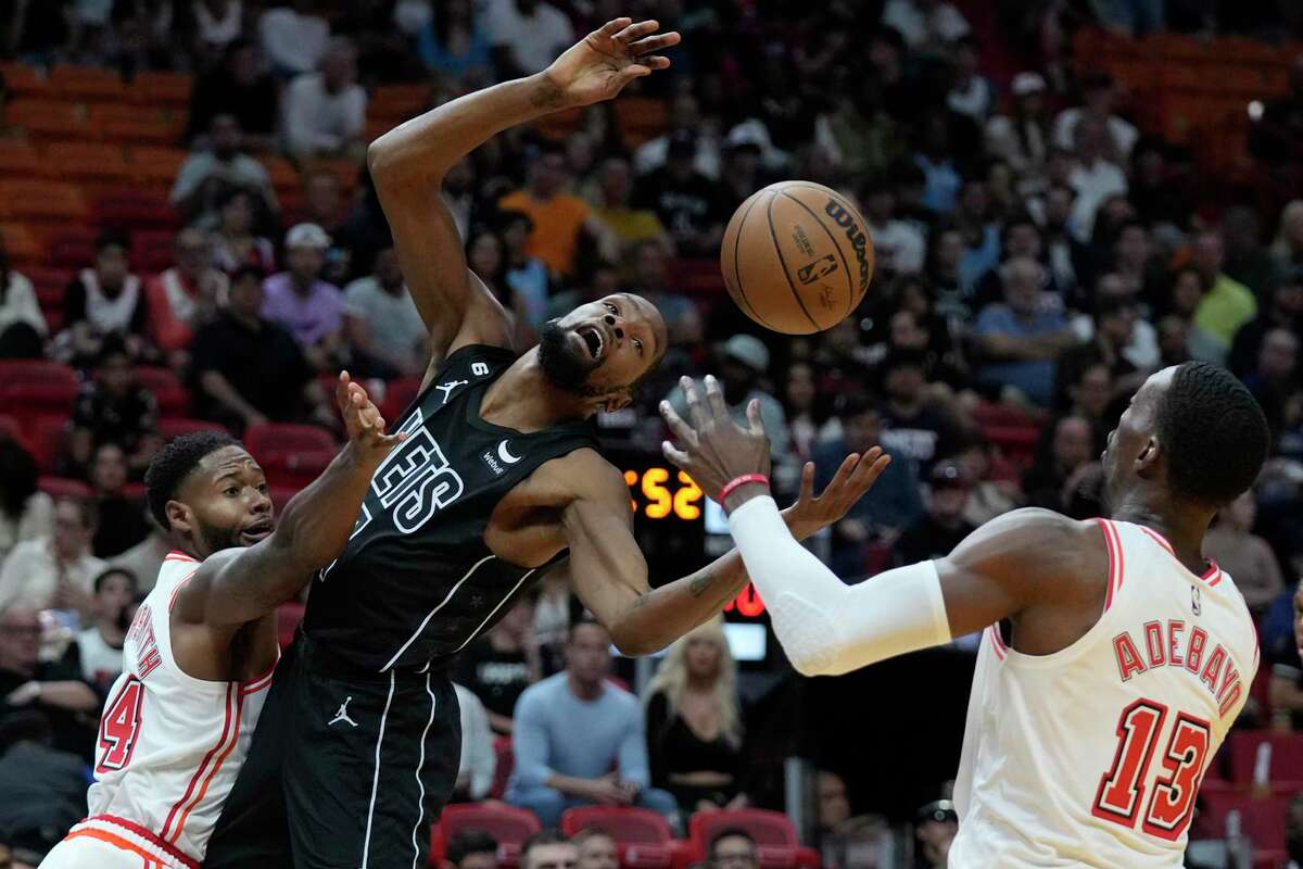 Miami Heat forward Haywood Highsmith, left, swats the ball away from Brooklyn Nets forward Kevin Durant, center, as center Bam Adebayo (13) attempts to catch the ball during the first half of an NBA basketball game, Sunday, Jan. 8, 2023, in Miami. (AP Photo/Wilfredo Lee)