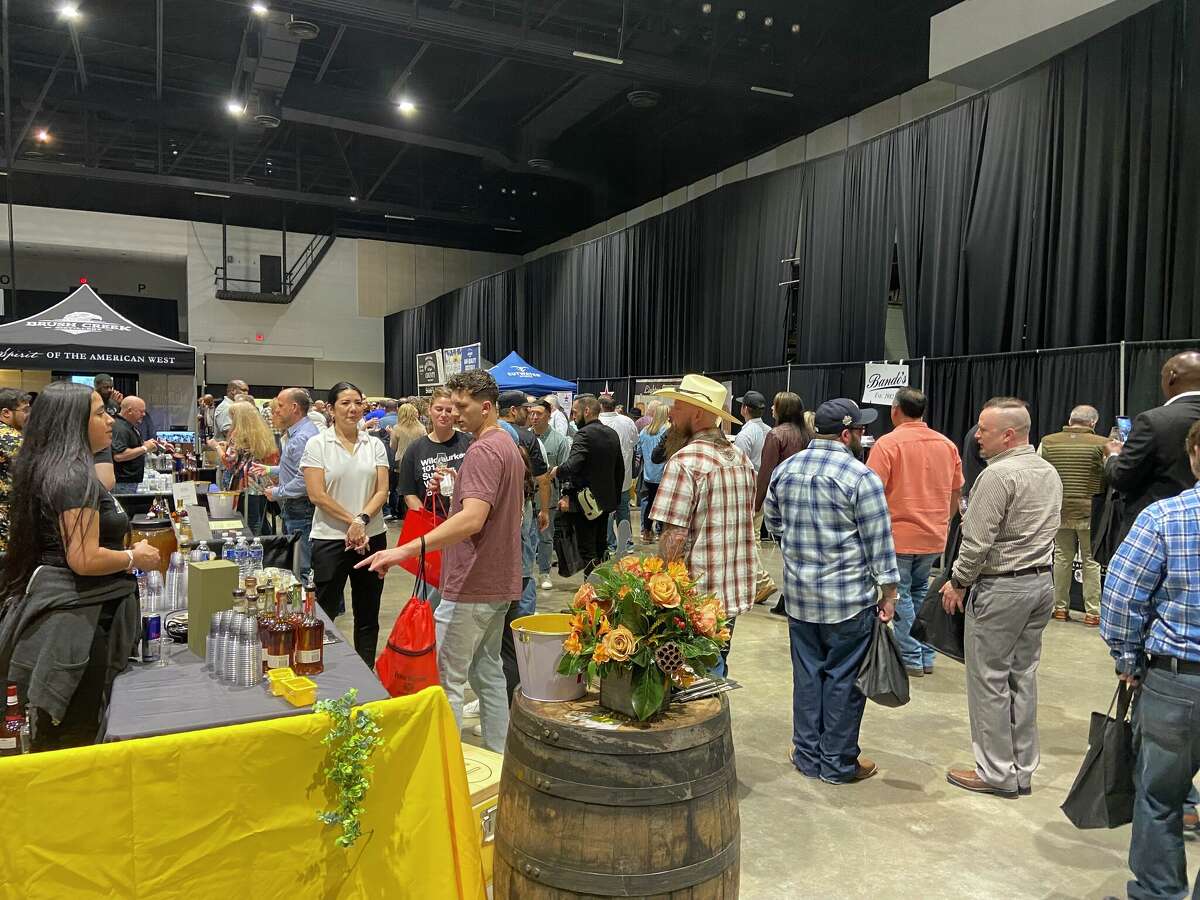 Event-goers wind through several whiskey-tasting booths.