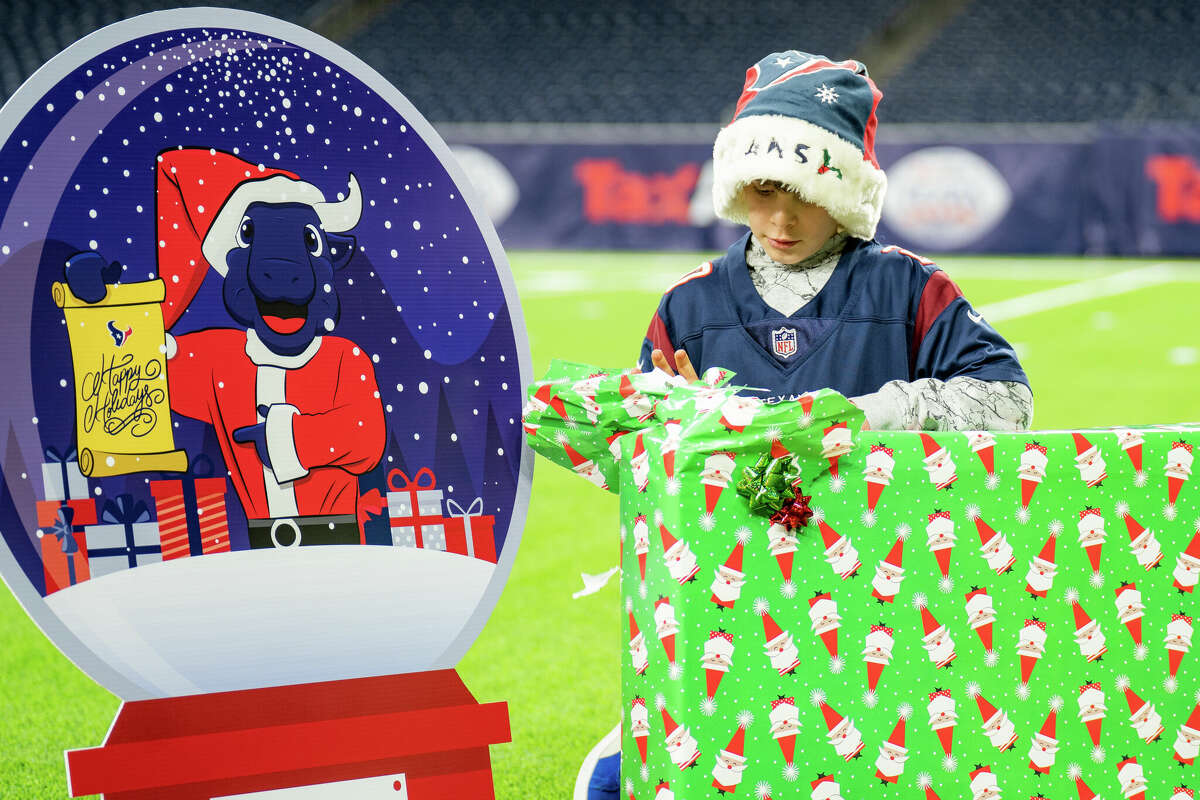 Brian Hunt, 11, from Kingwood tears into a present at the Letters to Santa Community Development Event with TORO at NRG Stadium in Houston, TX on Dec. 19, 2022.