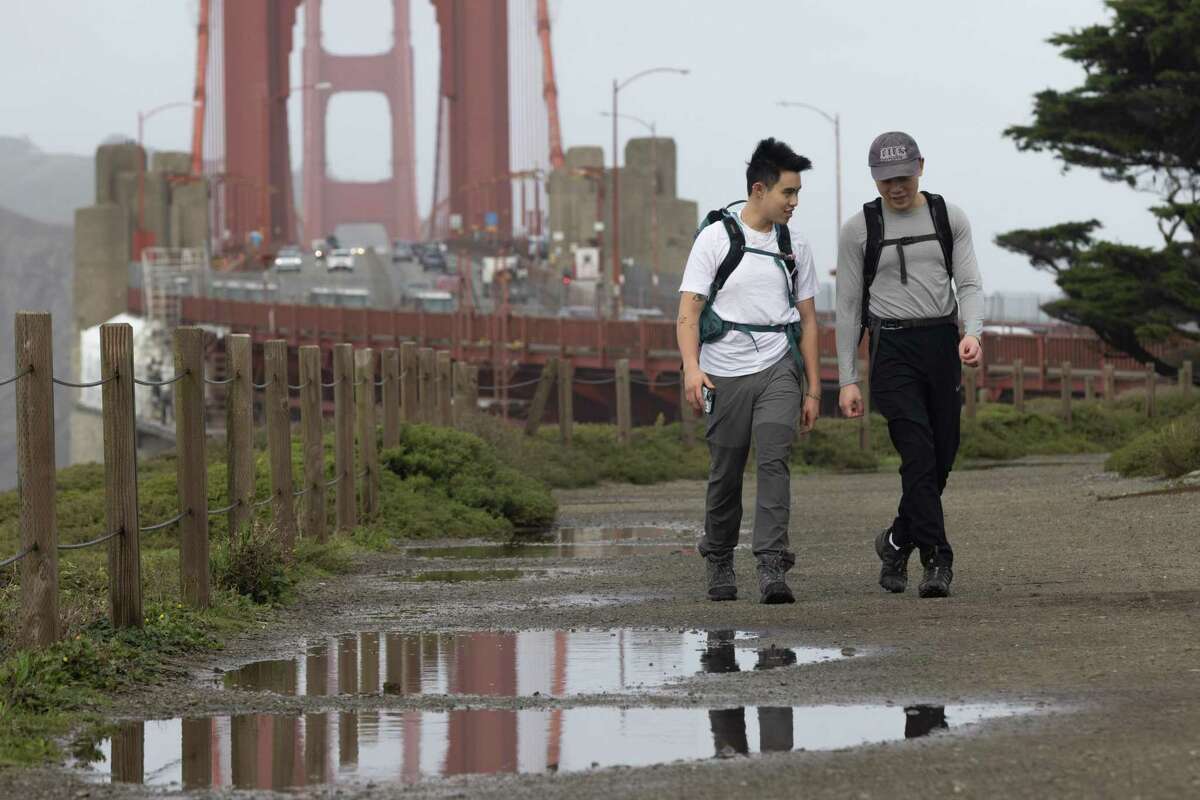 Stephen Le (left) and Brian Tang walk on a trail filled with puddles near the Golden Gate Bridge on Monday. Continuous rain has eased California’s drought emergency, but all of the state remains abnormally dry.
