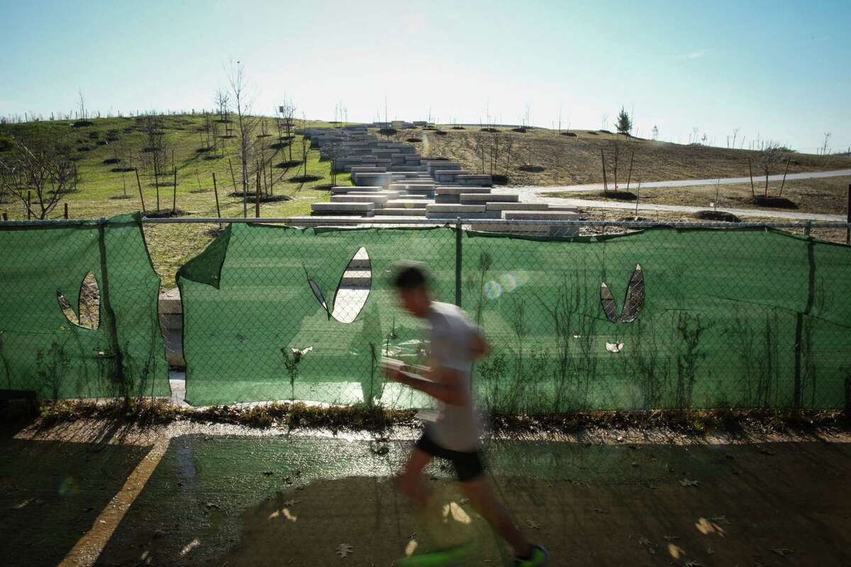 A jogger runs past work on the land bridge in Memorial Park. The land bridge is almost finished and is the newest project in the Memorial Park Conservancy's 10-year master plan.