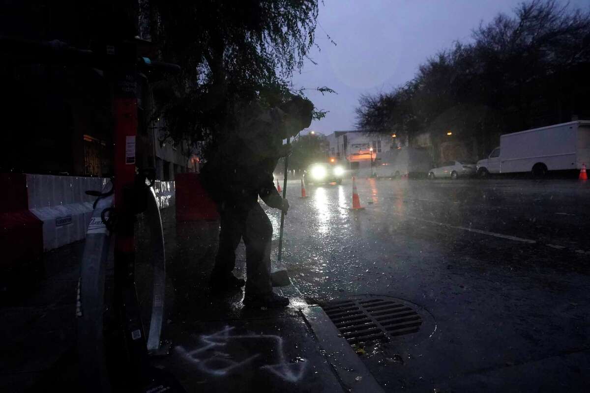 A resident watches as water flows into a sewage drain in San Francisco on Jan. 4.