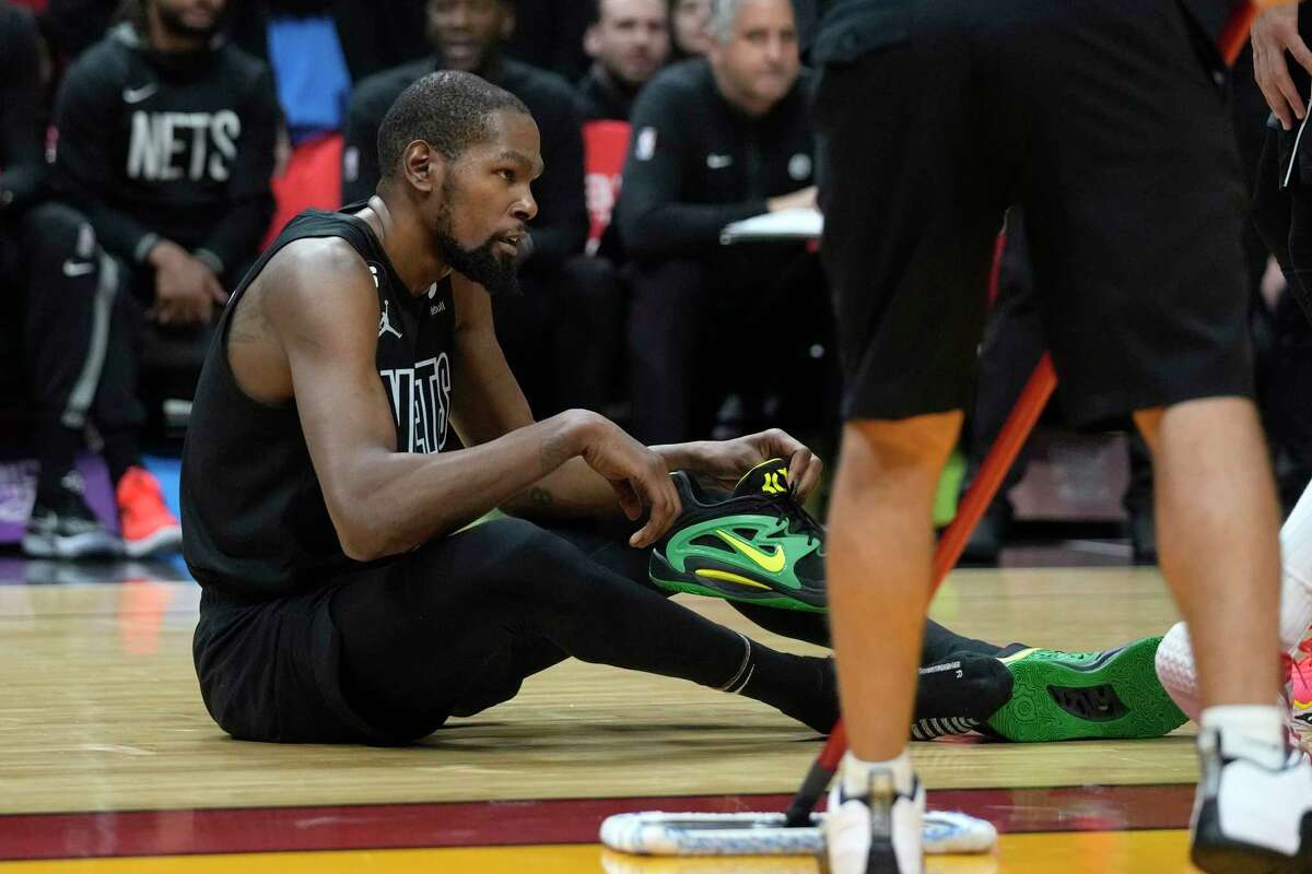 Brooklyn Nets forward Kevin Durant puts his shoe back on after a play during the second half of an NBA basketball game against the Miami Heat, Sunday, Jan. 8, 2023, in Miami. (AP Photo/Wilfredo Lee)