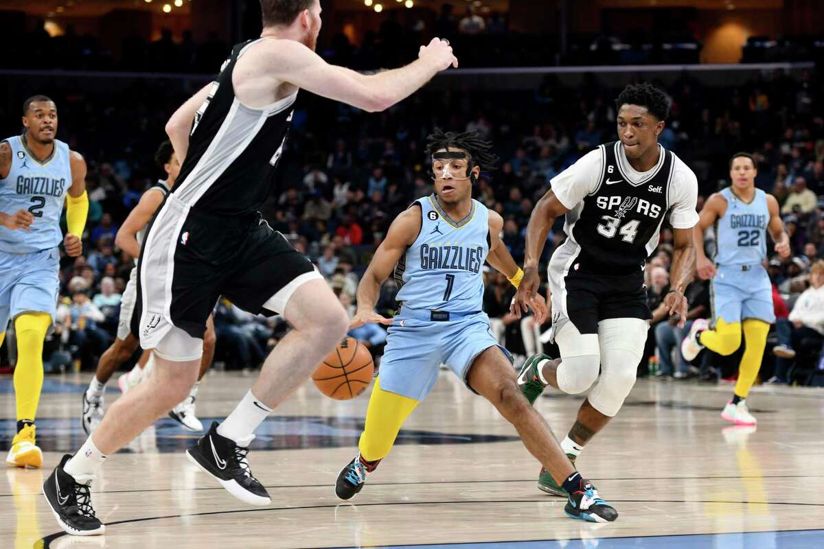 Memphis Grizzlies guard Kennedy Chandler (1) handles the ball between San Antonio Spurs forward Stanley Johnson (34) and center Jakob Poeltl, front left, in the first half of an NBA basketball game Monday, Jan. 9, 2023, in Memphis, Tenn. (AP Photo/Brandon Dill)
