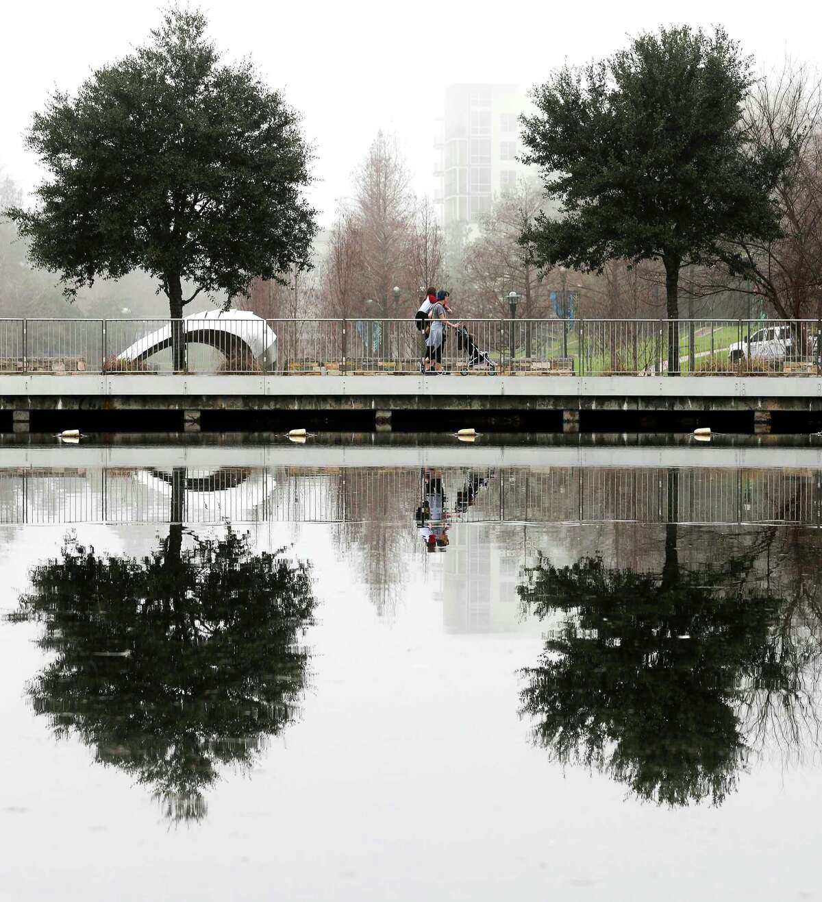 A family walks through fog around The Woodlands Waterway near Town Green Park, Tuesday, Jan. 10, 2022, in The Woodlands. Heavy flog blanketed the area Tuesday morning with temperatures in the mid-60s.