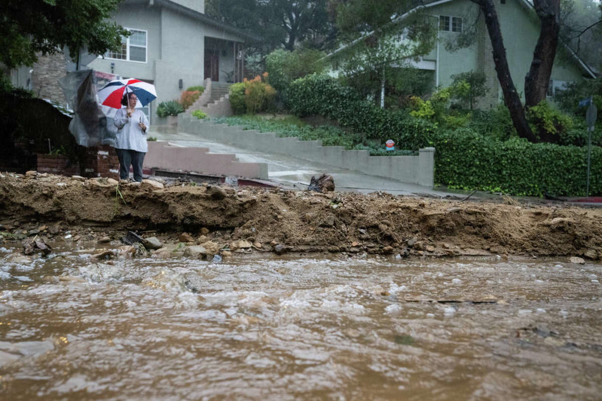 A resident keeps watch on Fredonia Drive in Studio City where a mudslide is blocking the road during the storm on Tuesday, Jan. 10, 2023.