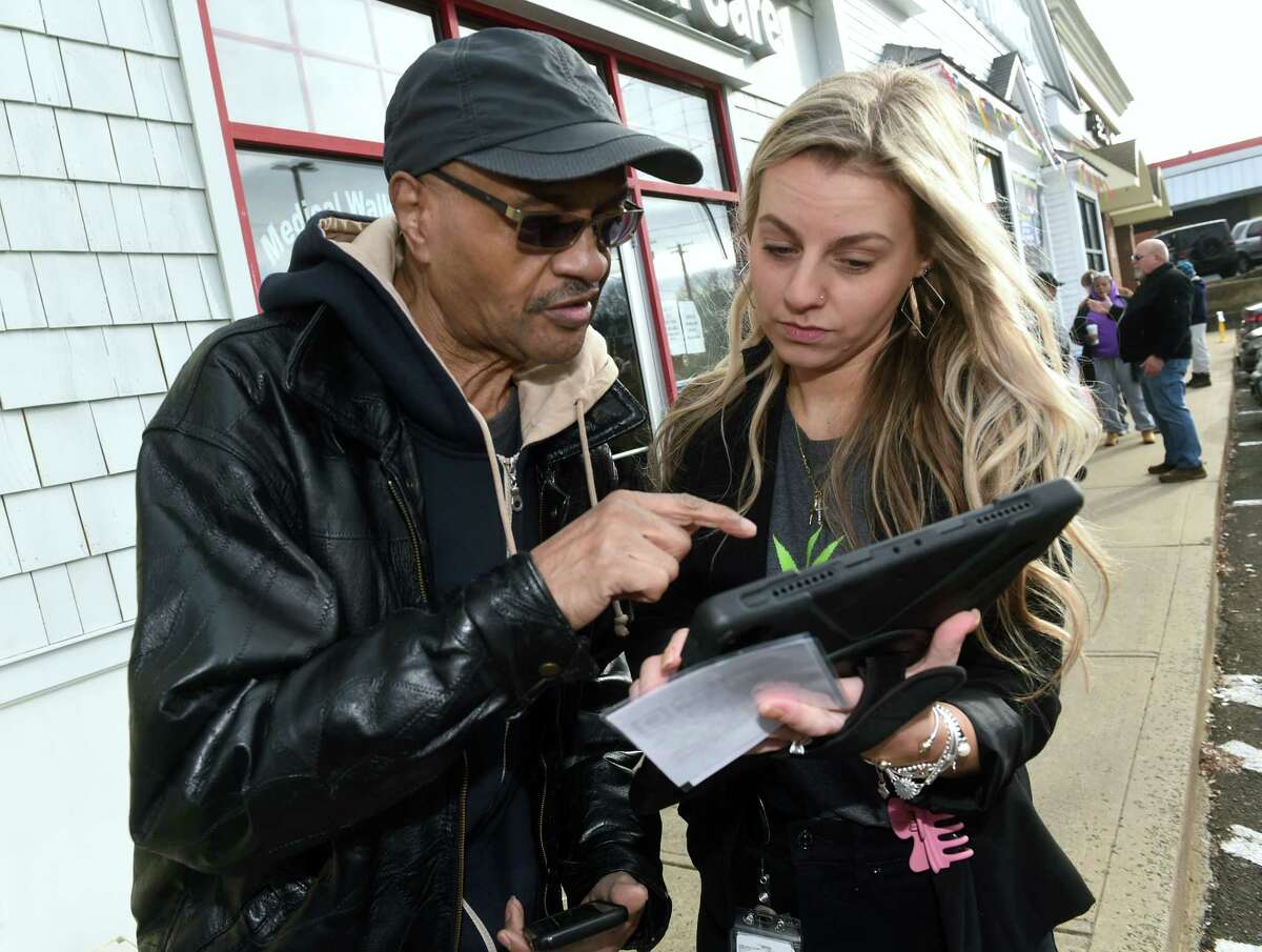 General Manager Gabbi Albert, right, assists Buck Medley of West Haven with his cannabis order at Affinity Health and Wellness on Whalley Avenue in New Haven on the first day of recreational cannabis sales Tuesday.
