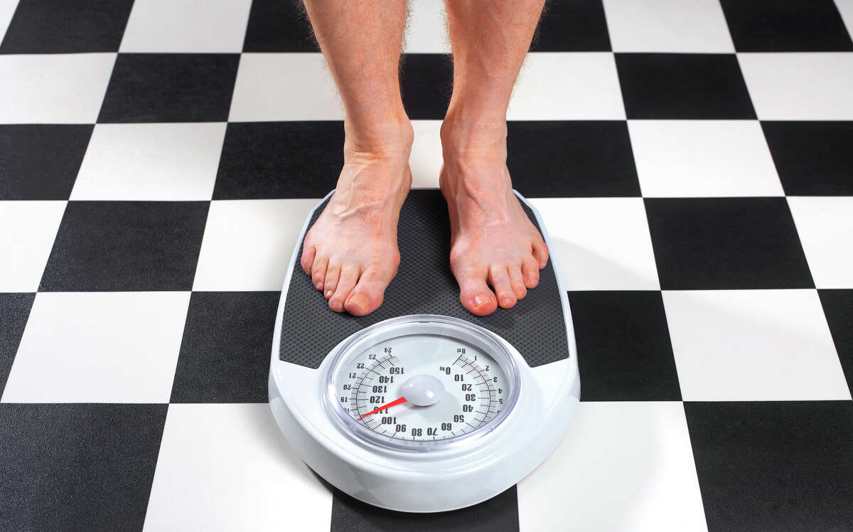 File photo of a man measuring his weight on a bathroom scale.