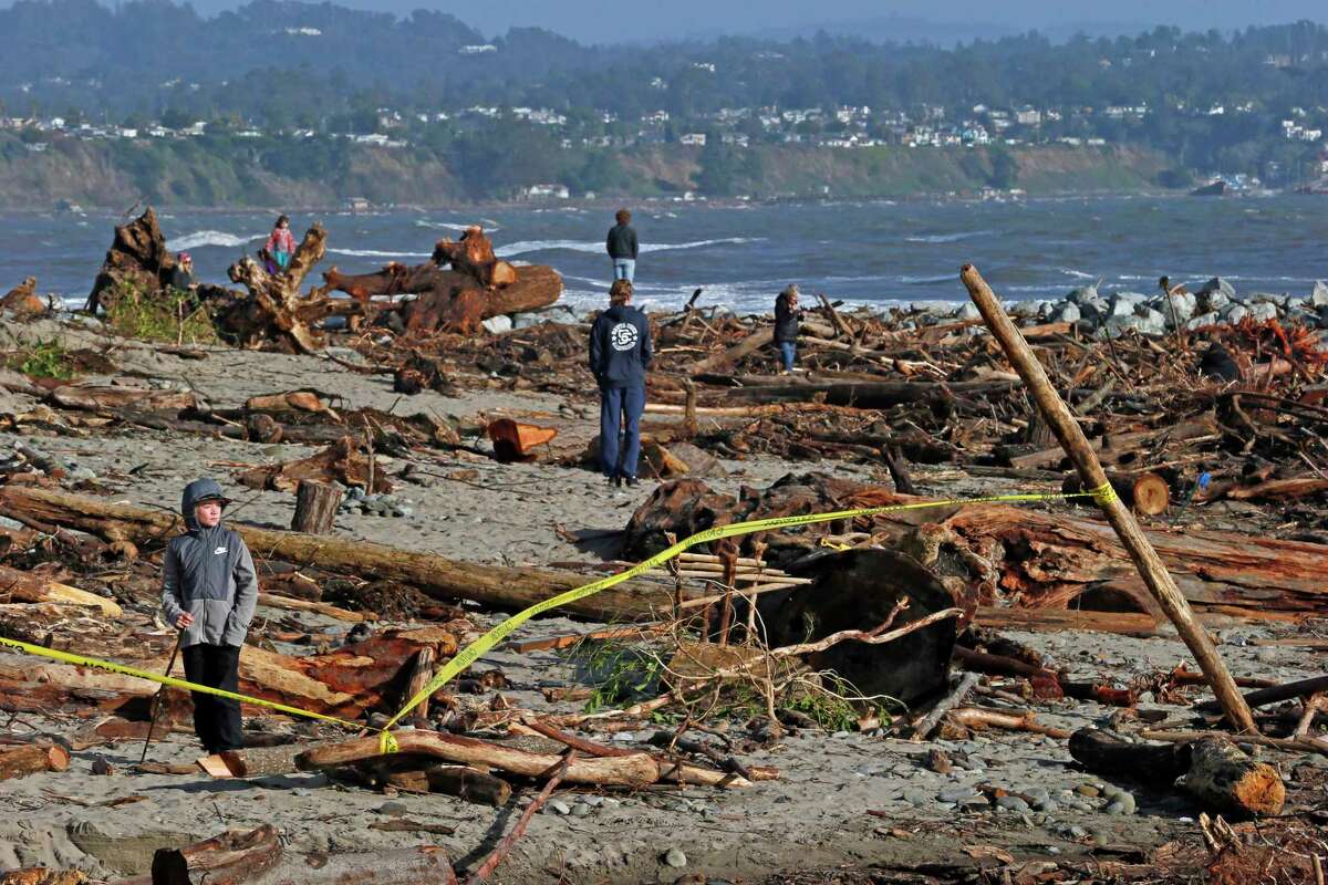 2023年1月10日星期二，11岁的加尔文·戴维斯在加州卡比托拉的警告胶带后面检查卡比托拉海滩的损坏情况。