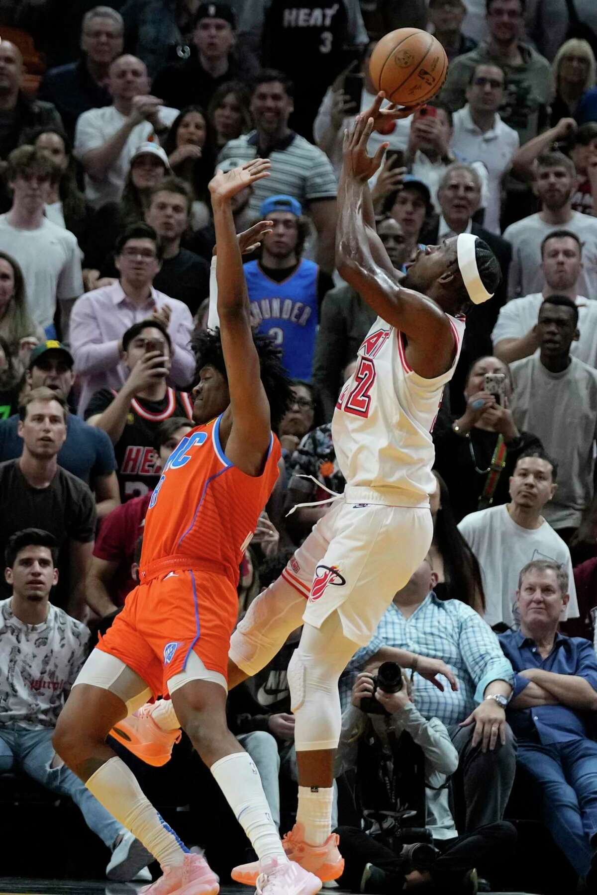 Miami Heat forward Jimmy Butler (22) scores against Oklahoma City Thunder guard Jalen Williams in the final seconds of the second half of an NBA basketball game, Tuesday, Jan. 10, 2023, in Miami. (AP Photo/Wilfredo Lee)