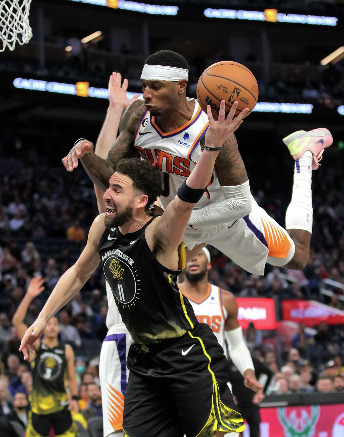 Torrey Craig (0) gets up ended as he fouls Klay Thompson (11) in the second half as the Golden State Warriors played the Phoenix Suns at Chase Center in San Francisco, Calif., on Tuesday, January 10, 2023.