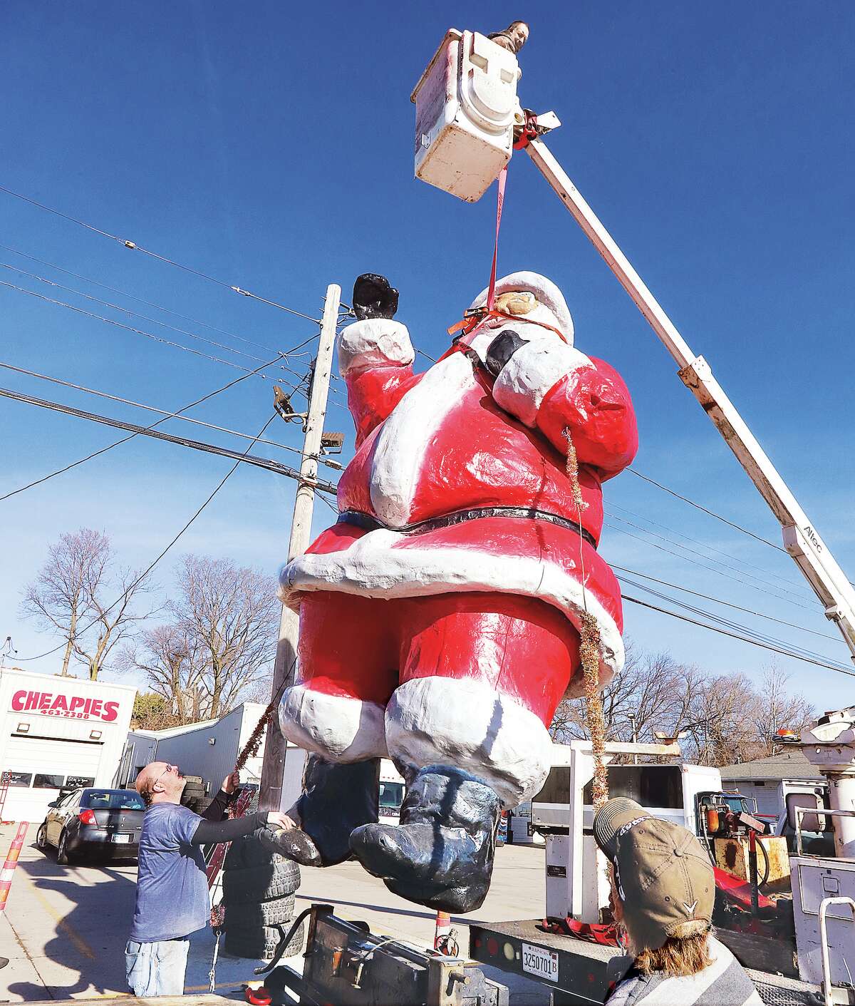 John Badman|The Telegraph Santa Claus couldn't escape being strung up this week in front of Cheapies tires, 3202 East Broadway in Alton. The large fiberglass figure, which has been around the area for decades, was being taken down for the season and placed on a flatbed trailer to head for storage. Employees guided the figure onto the trailer with help from Carl Dagnese and his bucket truck. During the off season, workers said Santa was going to receive some needed repairs and be repainted before he returns in December.