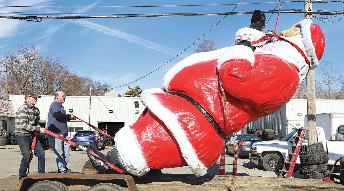 John Badman|The Telegraph Santa Claus is slowly lowered onto a flatbed trailer for storage and will return with repairs and a new paint job in December.