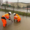 Caltrans workers Kyle Ingle, left, and Zach Westerhuis work to clear a drain next to Highway 101 in Paso Robles as a storm batters San Luis Obispo County on Jan. 9, 2023.