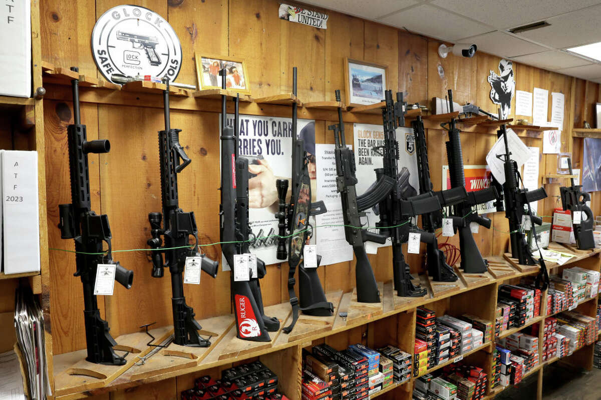 Assault-style rifles now banned for sale in the state are displayed at an Illinois sporting goods store. Workers began removing banned items from display shortly after the store opened Wednesday.