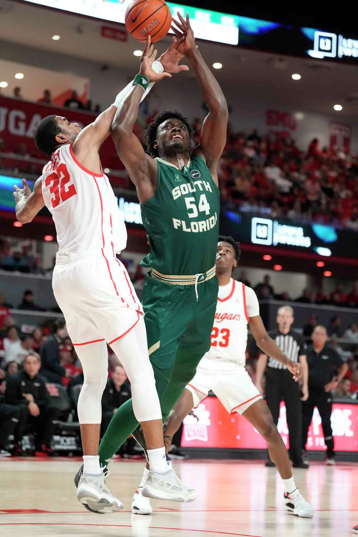 South Florida Bulls center Russel Tchewa (54) goes to he basket against Houston Cougars forward Reggie Chaney (32) during the first half of a NCAA mens basketball game at the Fertitta Center on Wednesday, Jan. 11, 2023 in Houston.