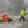 2022年12月31日星期六，加州蒙特雷68号国道车道上，一名加州交通运输公司的工作人员和一名加州公路巡警正在清理一棵被砍倒的树木。(美联社图片/Nic Coury)