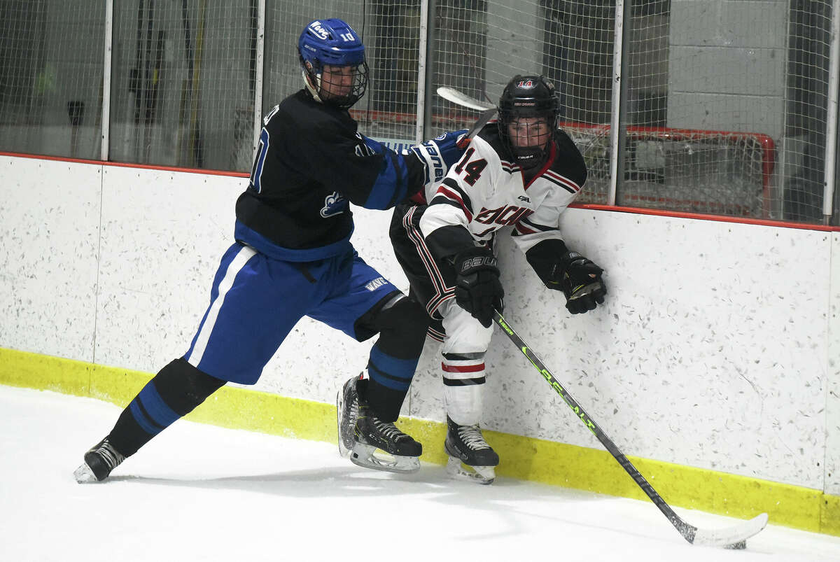 Darien's Graf Ely (10) and New Canaan's Gavin Fitzpatrick (14) mix it up along the boards during a boys ice hockey game at the Darien Ice House on Wednesday, Jan. 11, 2023.
