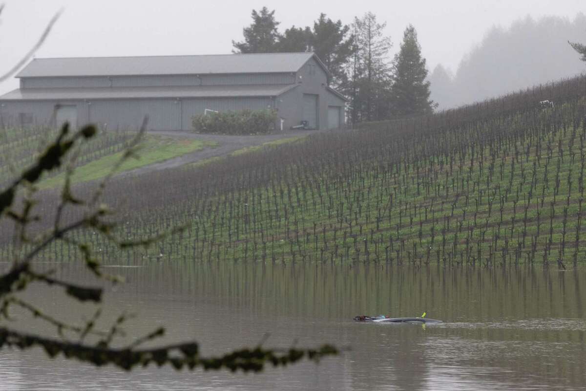 The top of a car is marked with flotation devices in the flooded area of a vineyard along the 6000 block of Trenton-Healdsburg Road in Forestville on Wednesday. Sonoma Sheriff’s Twitter account announced they had recovered the body of a 43-year-old individual from a submerged car in the area.
