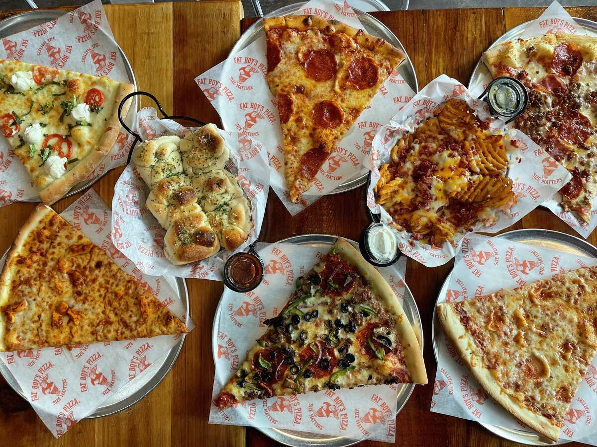 An assortment of food from Fat Boy's Pizza, including pizza, garlic knots and waffle fries.