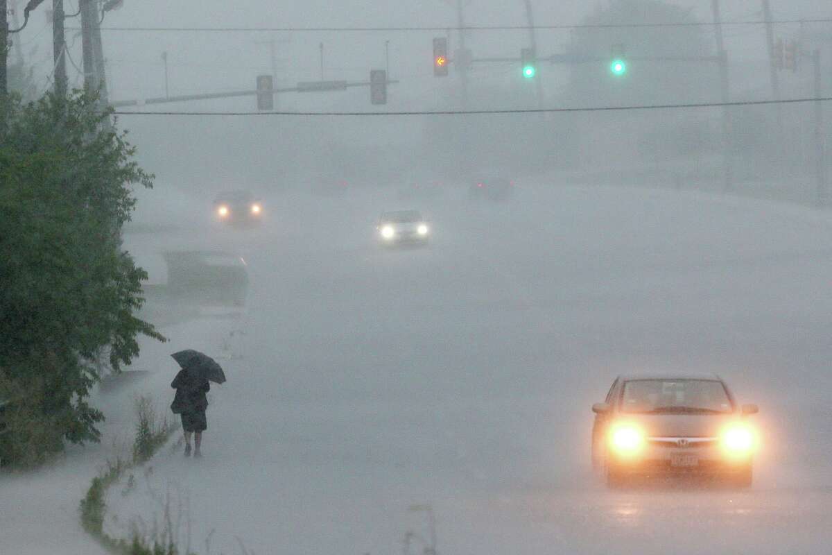 A pedestrian walks along Potranco Road as heavy rains move through the area, Monday, May 26, 2014. 
