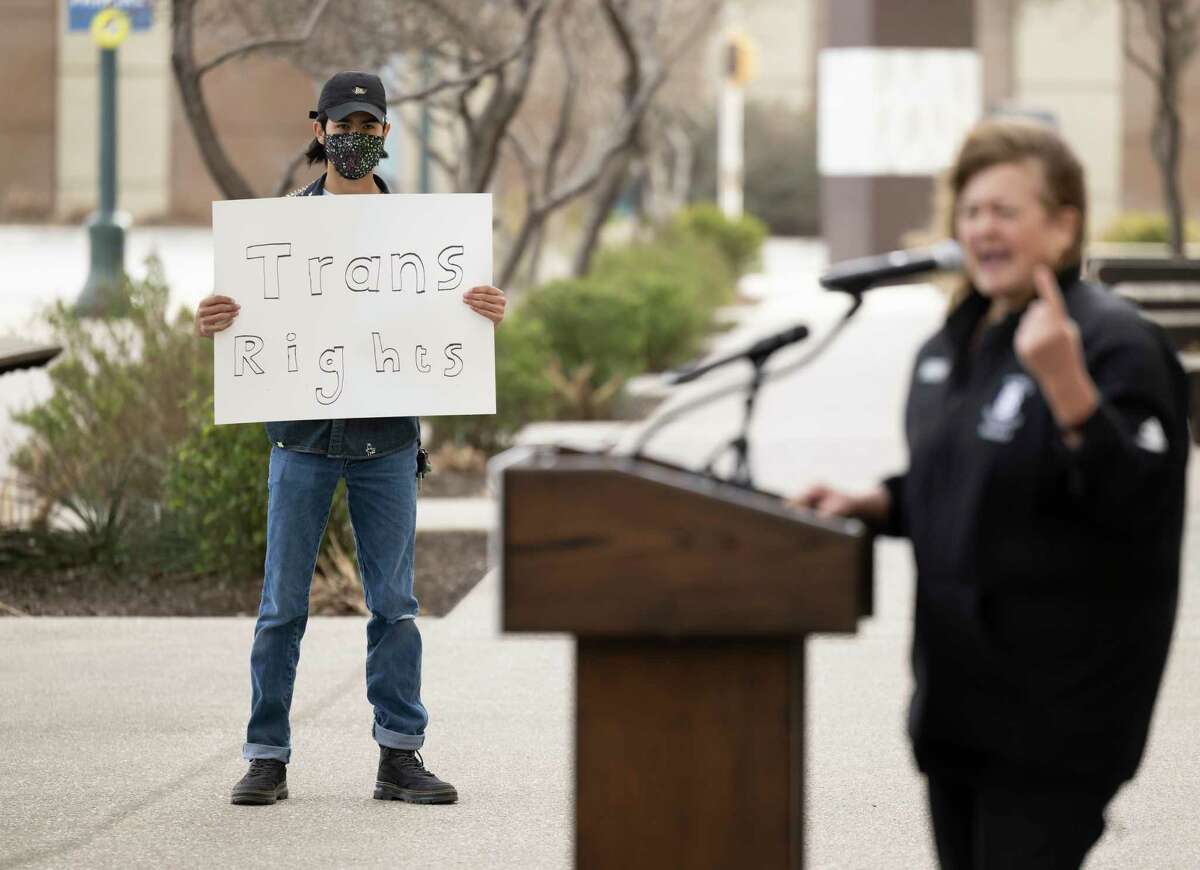 A trans rights activist holds a sign while Idaho state rep. Barbara Erhardt, right, speaks during a rally on Thursday, Jan. 12, 2023, outside of the NCAA Convention in San Antonio.