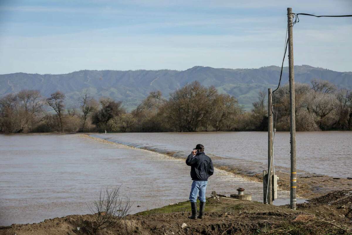 一名男子看着萨利纳斯河决口淹没了他在萨利纳斯河路附近的田地。