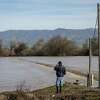 2023年1月12日星期四，加州萨利纳斯，一名不愿透露姓名的男子一边打电话，一边看着萨利纳斯河的决口淹没了他的田地。这名男子说，入侵发生在今天早上。在接下来的几天里，蒙特利县官员警告说，从查拉尔西南部到斯普雷克尔斯和河流公路走廊的萨利纳斯河沿岸可能发生洪水，可能导致严重的道路封闭，暂时切断半岛和萨利纳斯之间的交通。
