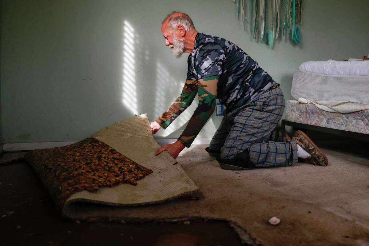 John Beard, the photographer’s stepfather, pulls up carpeting destroyed by floodwaters in his home.