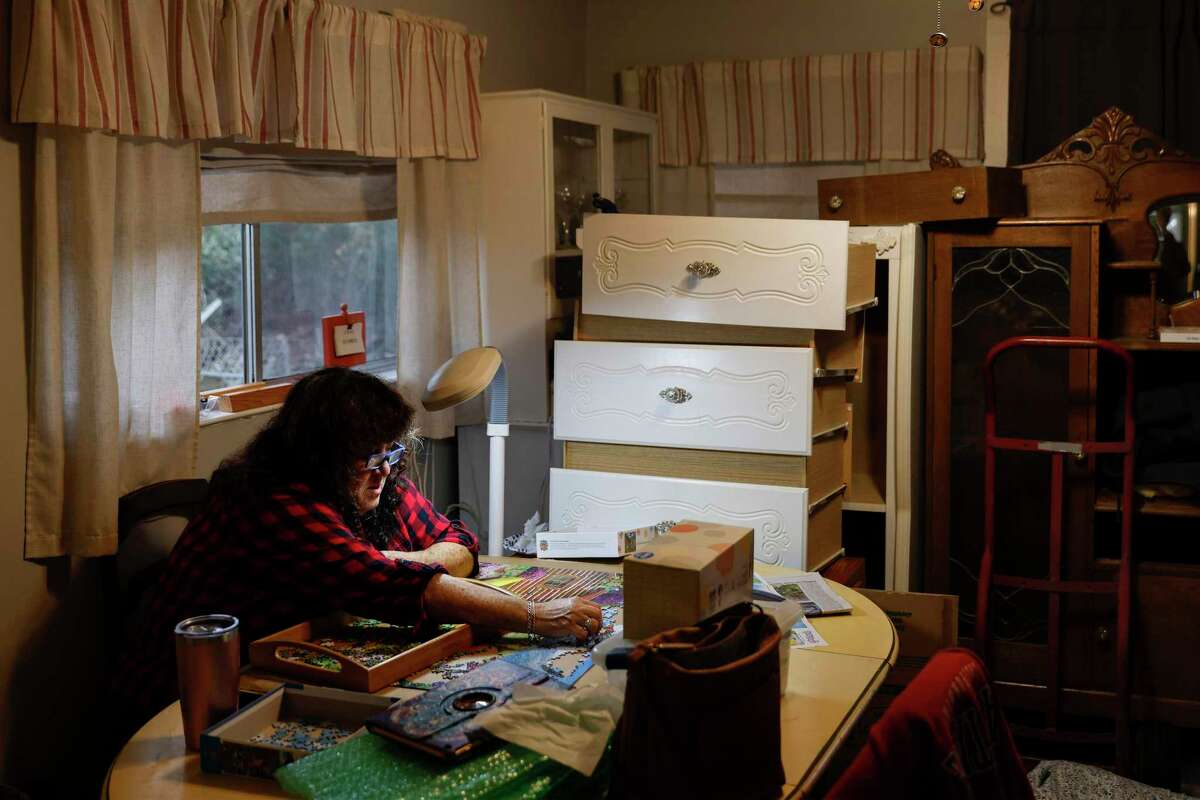 Surrounded by furniture removed from her flooded bedroom, Victoria Christian tries to relax by working on a jigsaw puzzle.