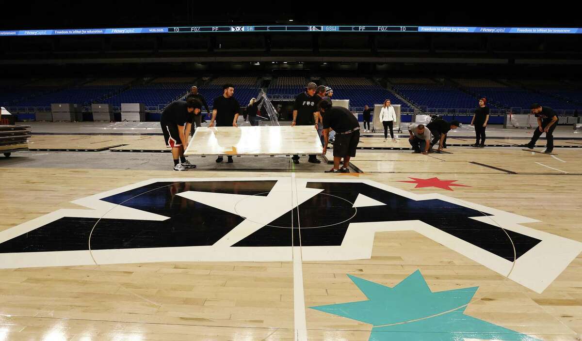 Work crews begin the tedious work of laying out the Spurs basketball court at the Alamodome on Monday, Jan. 9, 2023. As part of the organization’s 50th anniversary, the Spurs will play the Golden State Warriors at the Alamodome to a potentially record-breaking audience. The Spurs are looking to have nearly 65,000 fans pack the dome on Friday.