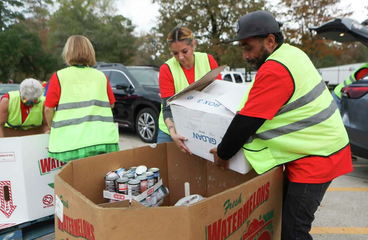 Volunteers Dale Bryor and Katie Melber carry a box of donated items to be sorted for the Montgomery County Food Bank's annual holiday food and funds fundraiser, Friday, Dec. 2, 2022, in Conroe. 