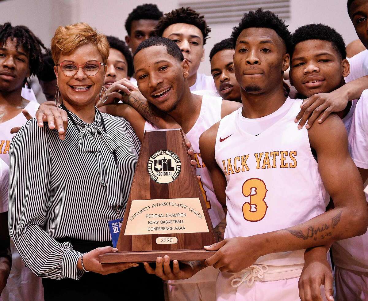 Yates High School principal Tiffany Guillory, left, holds the champions' trophy with the team after the team's win in a Class 4A regional final high school basketball game, Saturday, March 7, 2020, in Huntsville, TX.