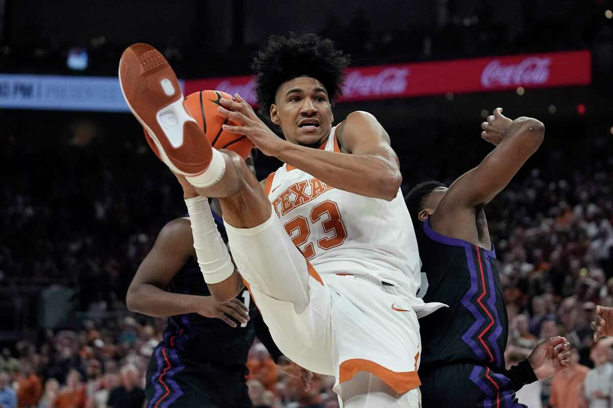Texas forward Dillon Mitchell (23) grabs a rebound next to TCU guard Shahada Wells, right, during the second half of an NCAA college basketball game in Austin, Texas, Wednesday, Jan. 11, 2023. (AP Photo/Eric Gay)