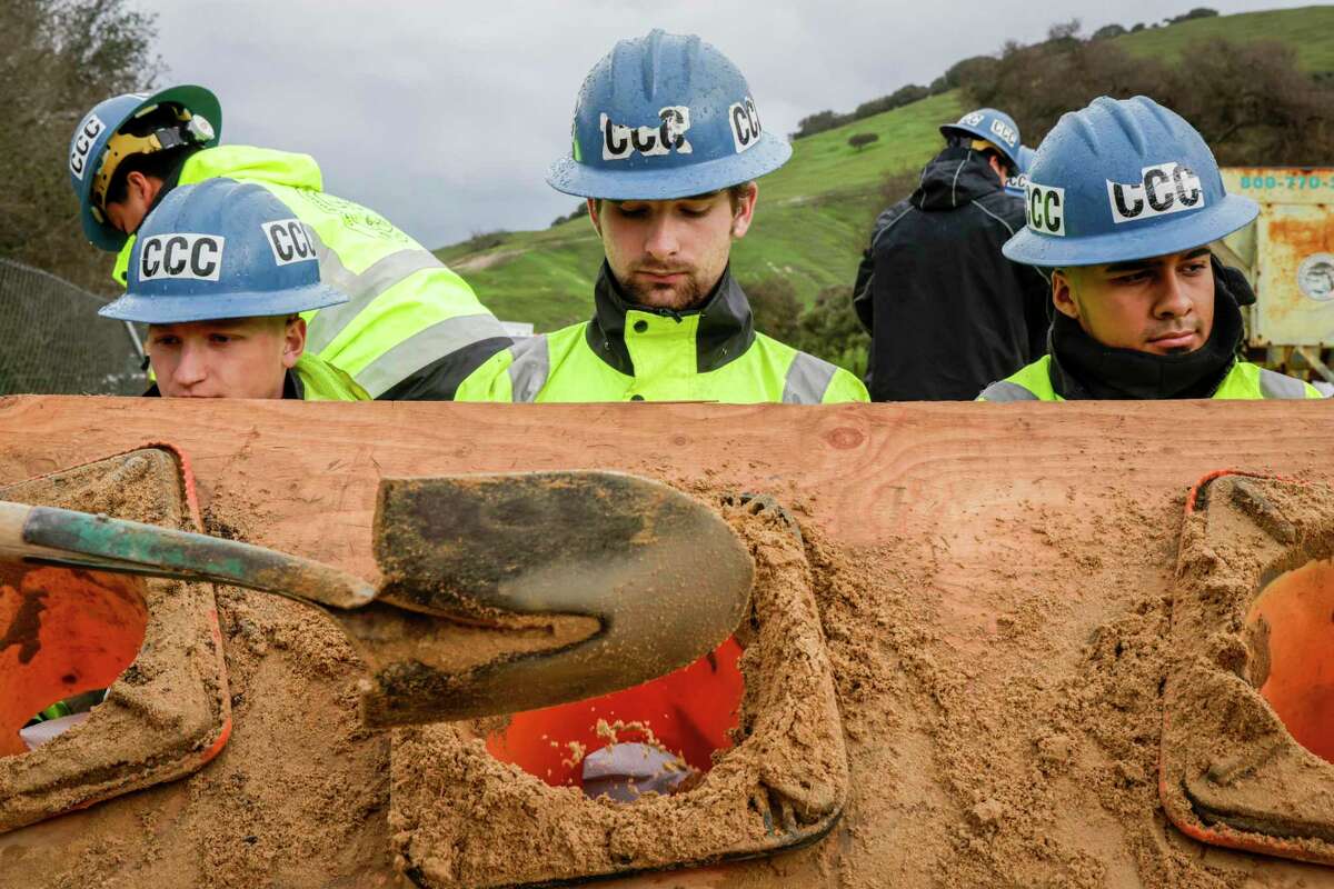Travis Carson (left), 20, Cameron Luther and Jesús Rizo, both 21, of the California Conservation Corps fill sandbags for distribution along the Salinas River.