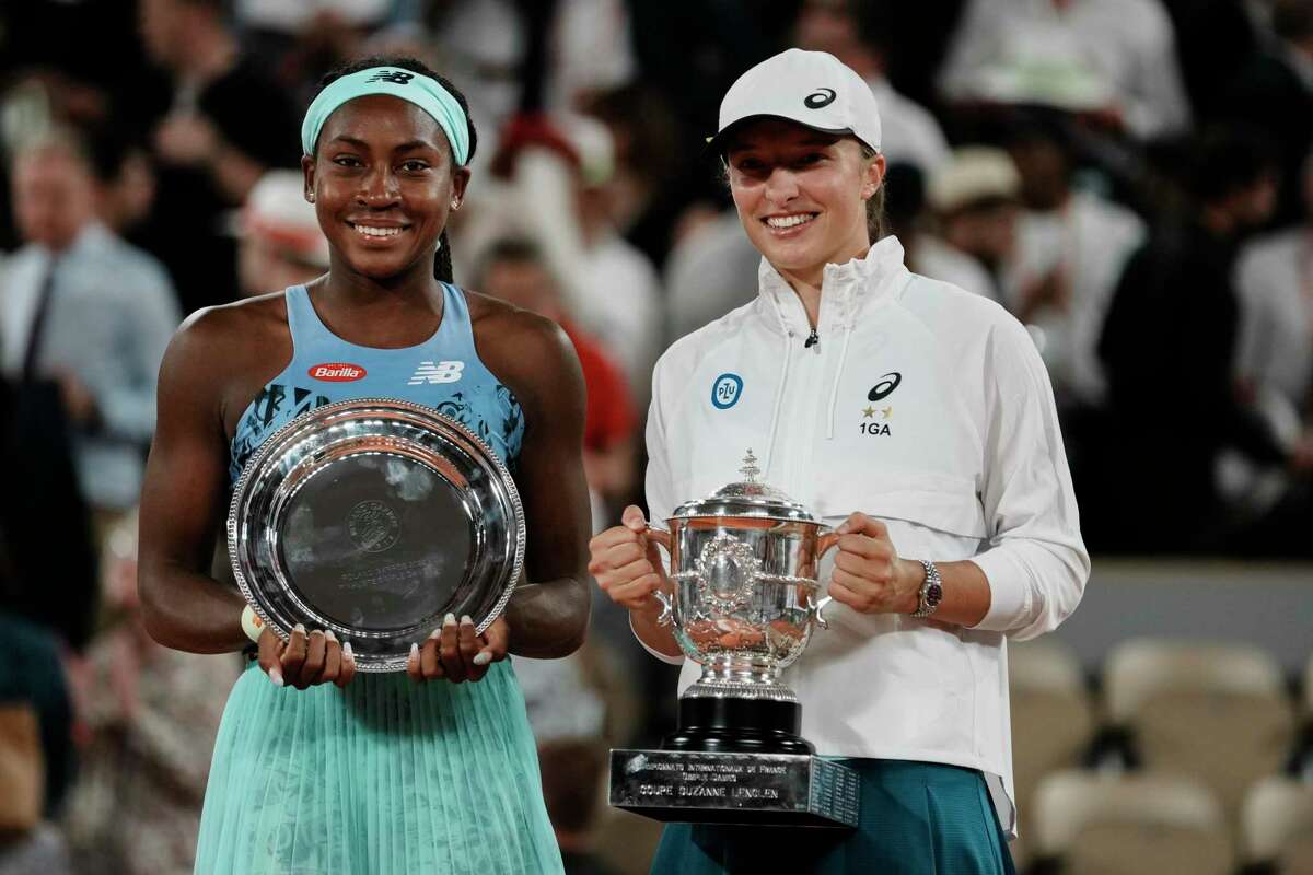 Poland’s Iga Swiatek (right) holds the trophy after defeating Coco Gauff (left) at the French Open on June 4, 2022.