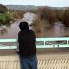 A passerby watches the rain-swollen Pajaro River in Watsonville on Jan. 12, 2023. Many homes in Watsonville suffered flood damage.
