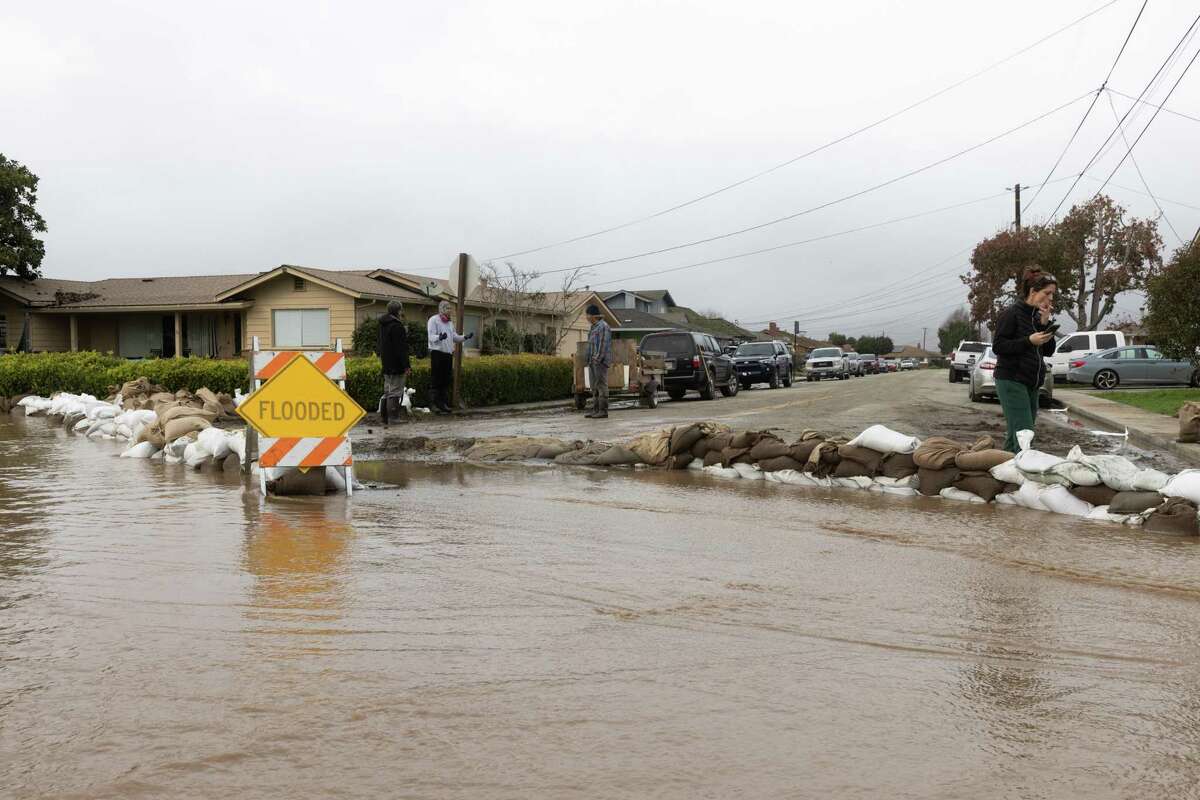 Neighbors use sandbags to stop floodwater from reaching homes off Holohan Road in Watsonville.