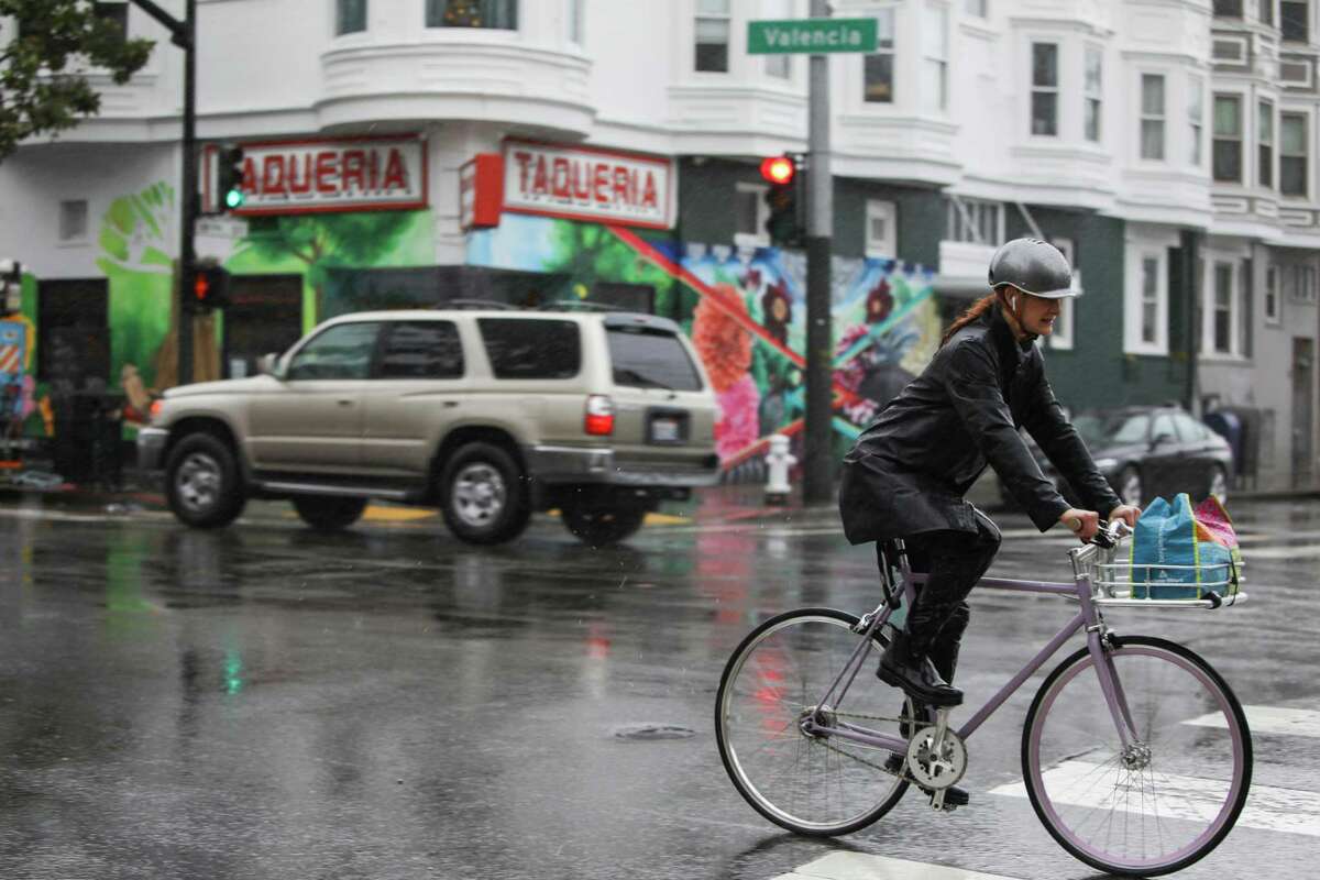 People ride bikes through the rainfall on Wednesday, Jan. 4, 2023 in the Mission District of San Francisco, Calif.