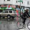 2023年1月4日，周三，在加利福尼亚州旧金山的教会区，人们在雨中骑自行车。