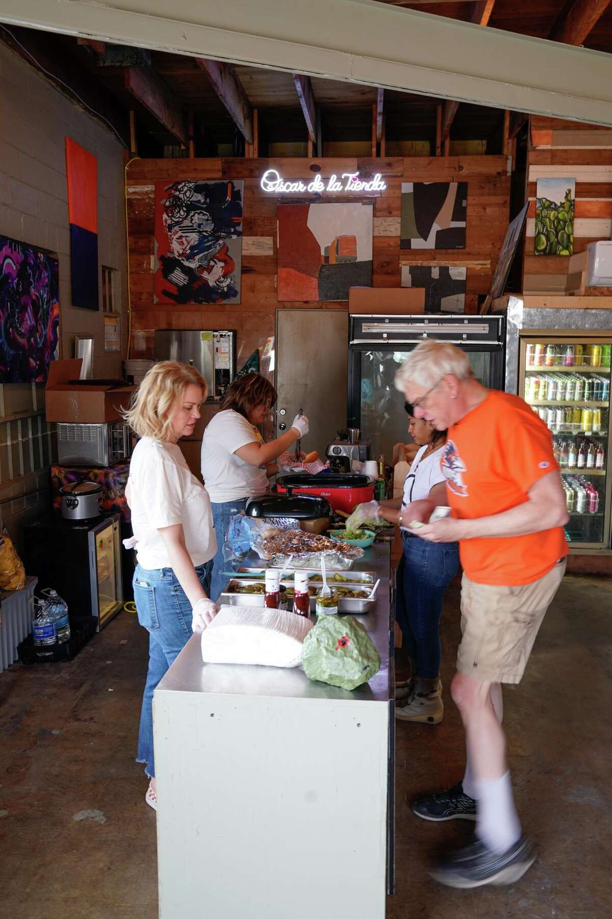 Vincent Michael orders a barbeque sandwich from Laura Wibracht during a benefit Sunday to help raise funds for Oscar de la Tienda, an eclectic convenience store in the Alta Vista neighborhood that serves as a hub for other small businesses and local artists without brick and mortar shops of their own. Gomez said construction has severely impacted business and the store is “hanging on by a thread, operating at 25% of what average revenues should be.”