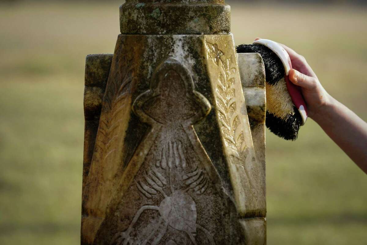 Bianca Scialabba, a recent college graduate who studied history, cleans a headstone Monday, Jan. 16, 2023, at an historic Black cemetery, in Bates M. Allen Park in Kendleton.