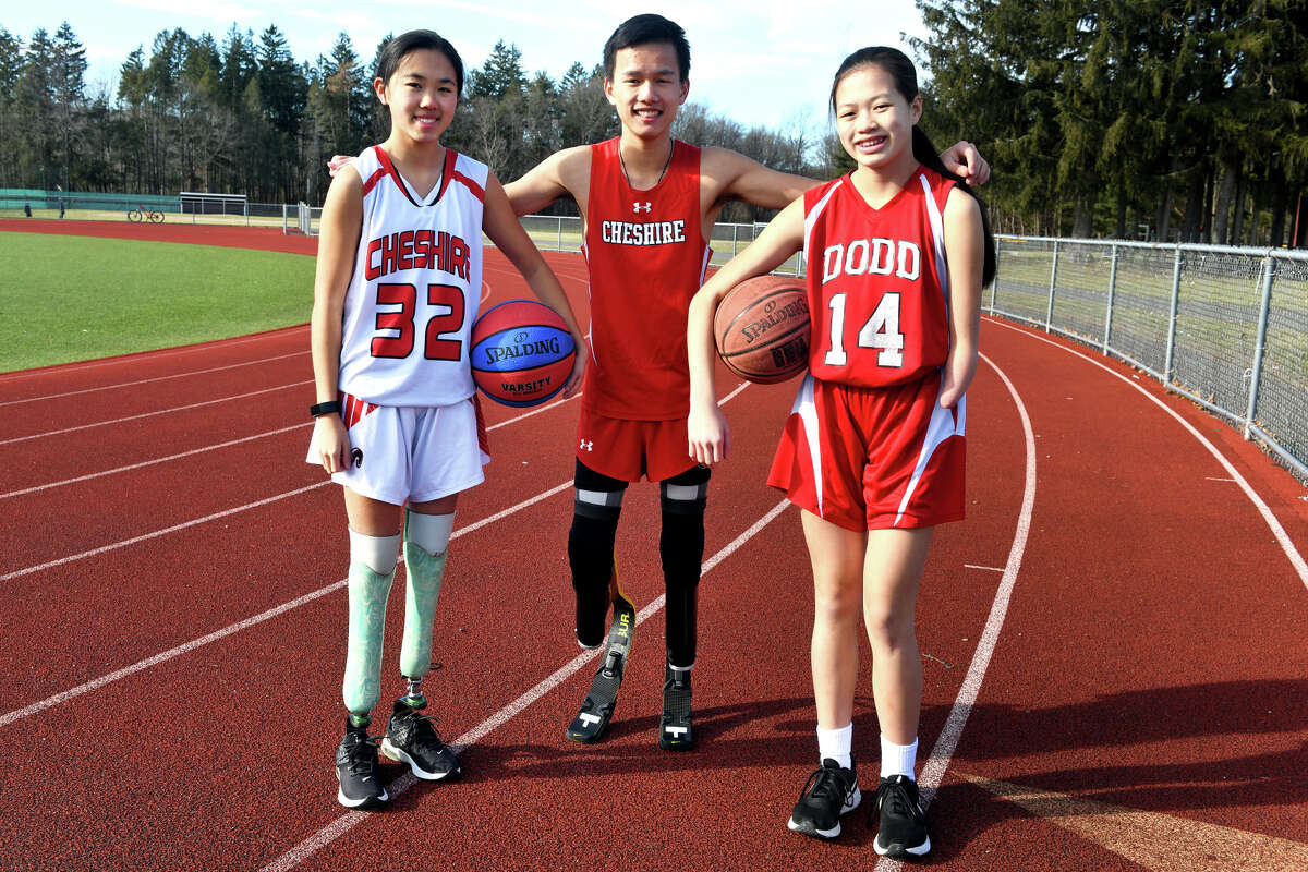 Cheshire High School sophomore track athlete Matthew Reid poses with his sisters, Sarah, left, and Emily, right, in Cheshire, Conn. Jan. 16, 2023. Sarah is a freshman basketball player at Cheshire High and seventh-grader Emily plays basketball at Dodd Middle School.