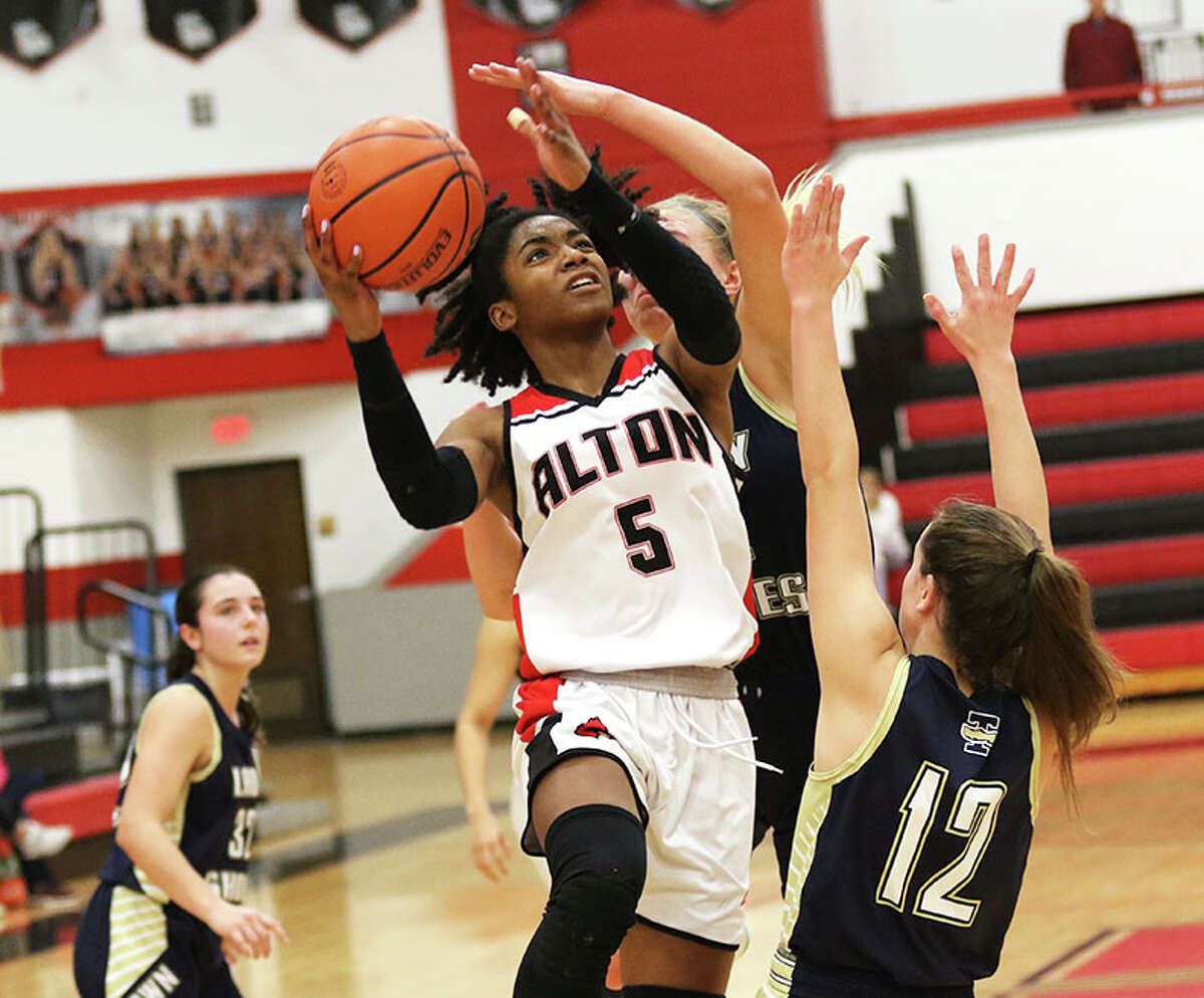 Alton's Kaylea Lacey (5) goes to the basket and shoots over T-Town's Joleen Deters in the first half Monday night at the Apex Network Physical Therapy & Fitness Center Tournament in Highland.