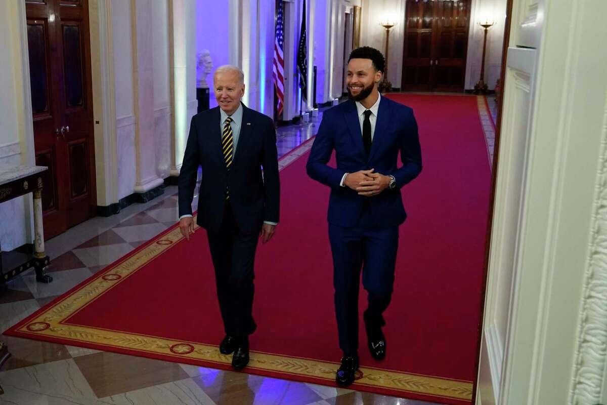 President Joe Biden arrives with Stephen Curry as he welcomes the 2022 NBA champions, the Golden State Warriors, to the East Room of the White House in Washington, Tuesday, Jan 17, 2023. (AP Photo/Susan Walsh)